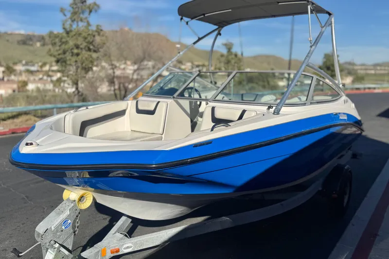 Slide: The Image of 2015 Yamaha Boats AR190, blue and white, on a trailer in a scenic outdoor setting. - 3