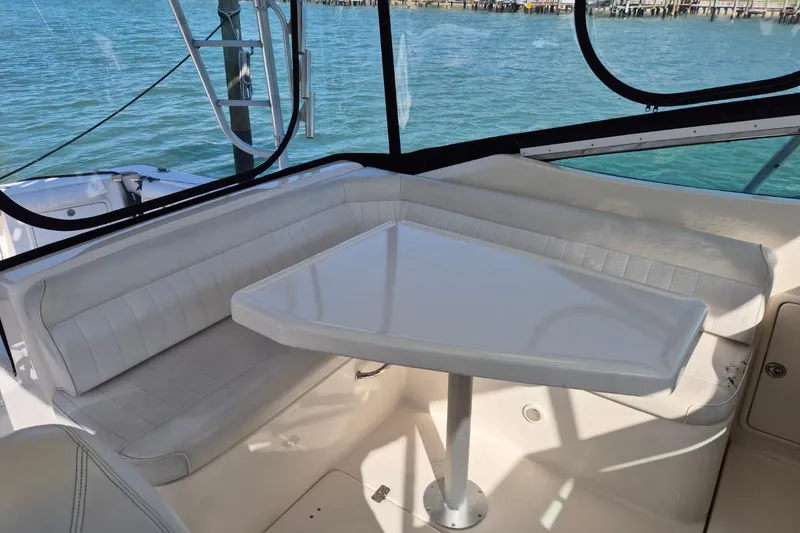 Slide: The Image of 2004 Riviera 4000 Offshore boat interior with white seating and table, overlooking the water. - 35