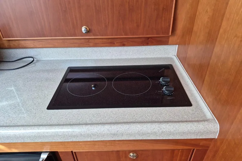 Slide: The Image of 2004 Riviera 4000 Offshore yacht kitchen with electric stovetop and wooden cabinetry. - 61