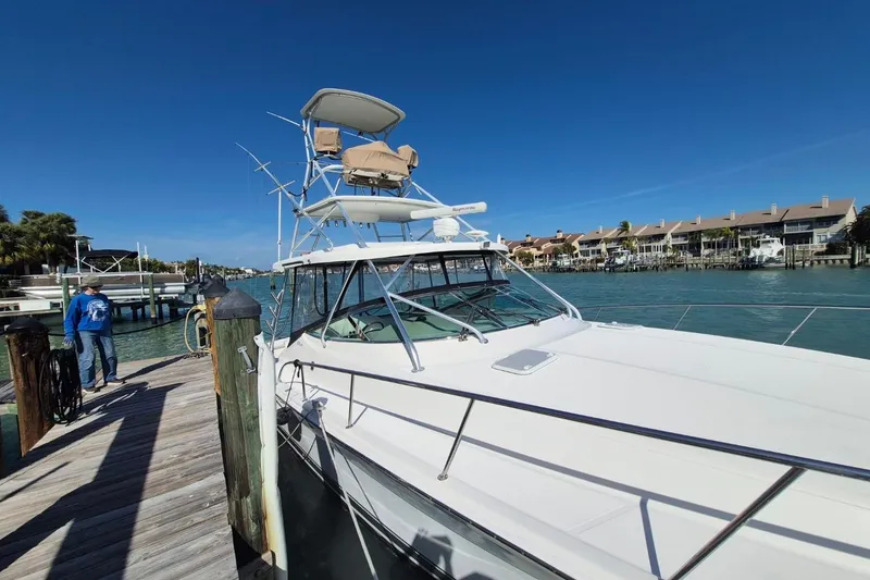 Slide: The Image of 2004 Riviera 4000 Offshore yacht docked by waterfront homes under clear blue sky. - 7
