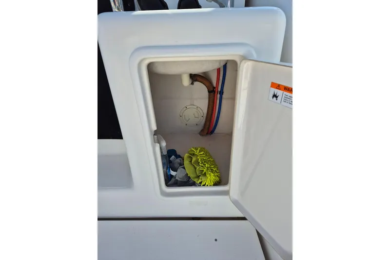Slide: The Image of Open storage compartment on 2004 Riviera 4000 Offshore boat with cleaning supplies. - 78