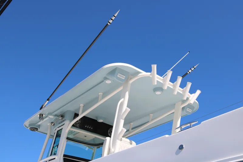 Slide: The Image of 2026 World Cat 325 CC boat roof with fishing rod holders against clear blue sky. - 6