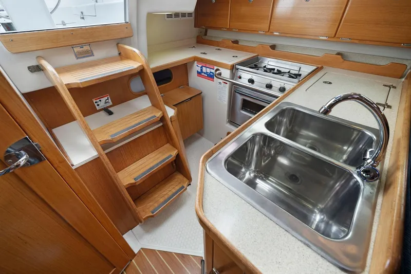 Slide: The Image of 2004 Catalina 36 MkII yacht interior with wooden cabinetry, dual sink, and compact kitchen. - 21
