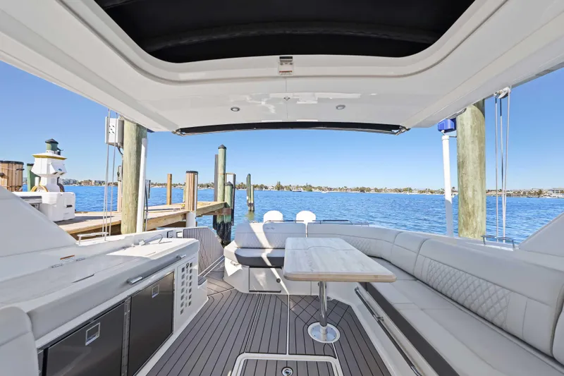 Slide: The Image of 2023 Sea Ray SLX 400 Outboard luxury boat interior with seating and table, docked by the water. - 25