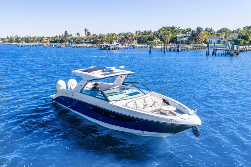 Slide: The Image of 2023 Sea Ray SLX 400 Outboard cruising on a sunny day in a scenic coastal area. - 2