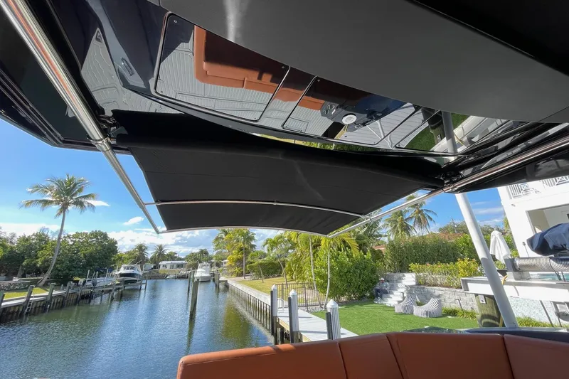 Slide: The Image of 2023 Cruisers Yachts 38 GLS I/O with retractable canopy, docked by a scenic canal. - 16