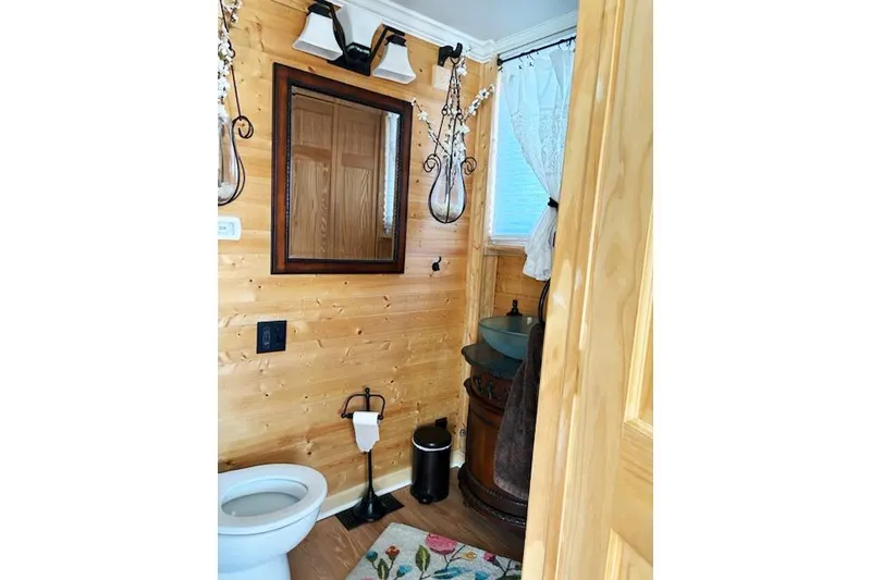 Slide: The Image of Wood-paneled bathroom on 1987 Kelly motor yacht with mirror, toilet, and decorative lighting. - 24