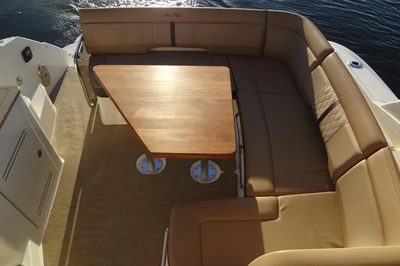 Slide: The Image of 2017 Sea Ray Sundancer 350 boat interior with tan seating and wooden table. - 21