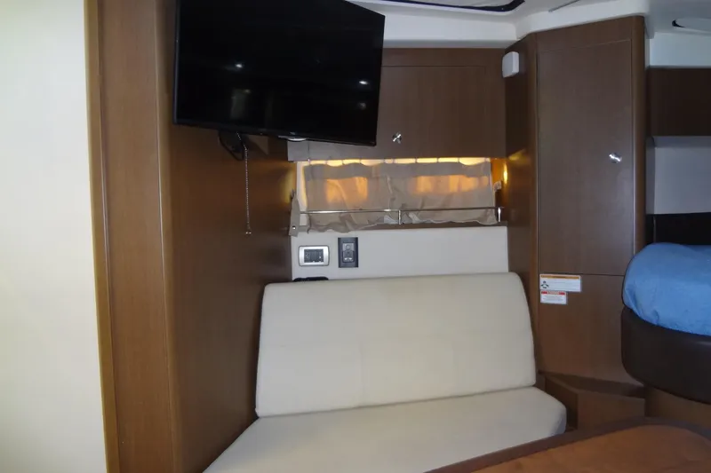 Slide: The Image of 2017 Sea Ray Sundancer 350 interior with TV, beige seating, and wooden cabinetry. - 41
