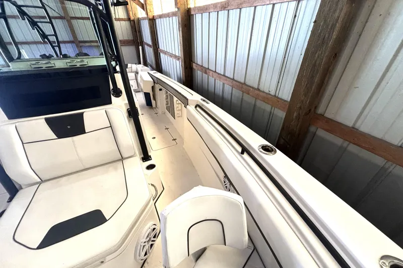 Slide: The Image of 2019 Wellcraft 302 Fisherman boat interior with white seating and storage, docked in a wooden shed. - 35