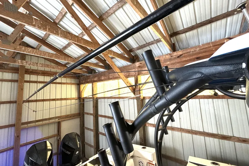 Slide: The Image of 2019 Wellcraft 302 Fisherman boat stored in a wooden shed with fishing rods. - 44