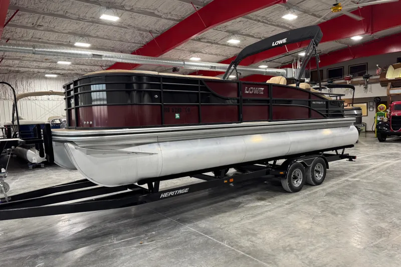 The Image of 2018 Lowe Retreat 250 RFL pontoon boat on trailer in indoor storage facility. - 1