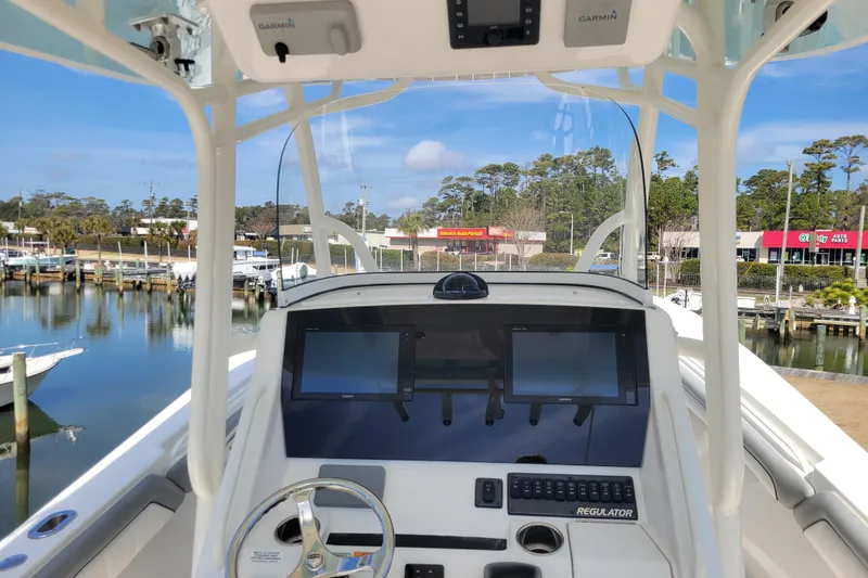 Slide: The Image of 2018 Regulator 28 Forward Seating boat dashboard with Garmin displays at a marina. - 4