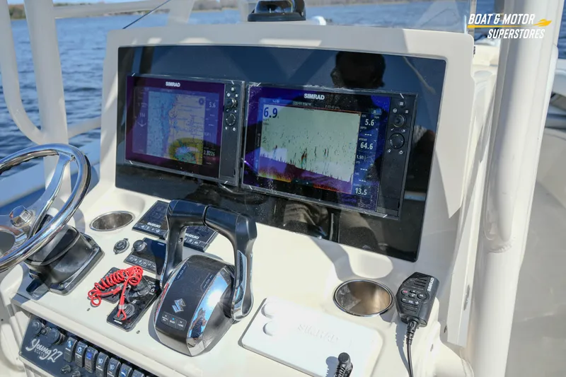 Slide: The Image of Boat dashboard with dual Simrad displays, steering wheel, and controls on a 2016 Young 27 model. - 21