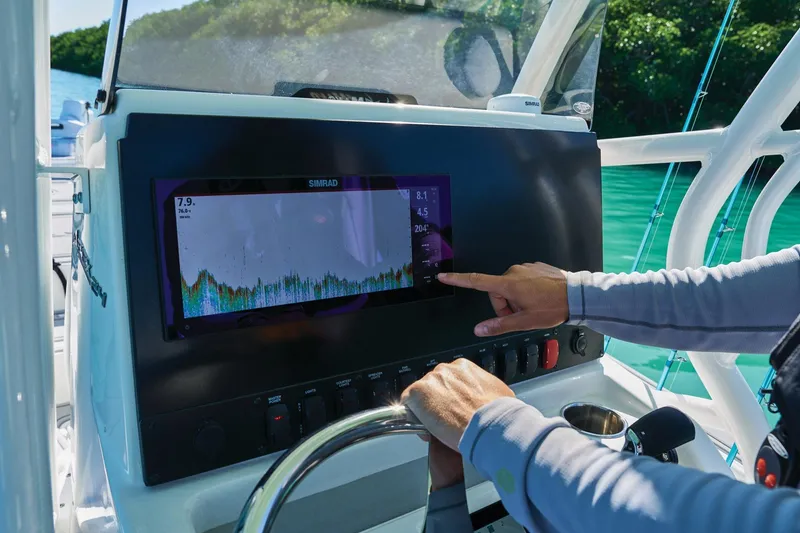Slide: The Image of Person operating navigation system on 2026 Mako 24 APEX boat in sunny waters. - 76