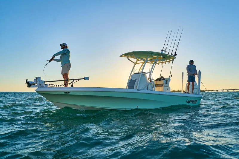 Slide: The Image of 2026 Mako 24 APEX boat with two people fishing at sunset on the ocean. - 80
