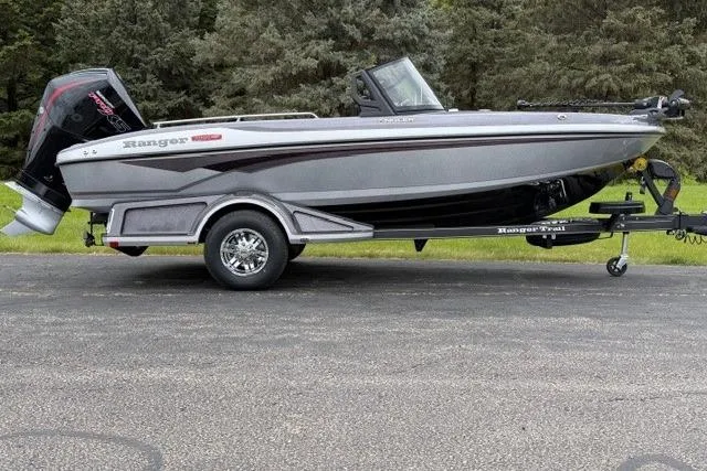 The Image of 2026 Ranger 1880MS boat on trailer, sleek design, parked on asphalt with trees in background. - 0