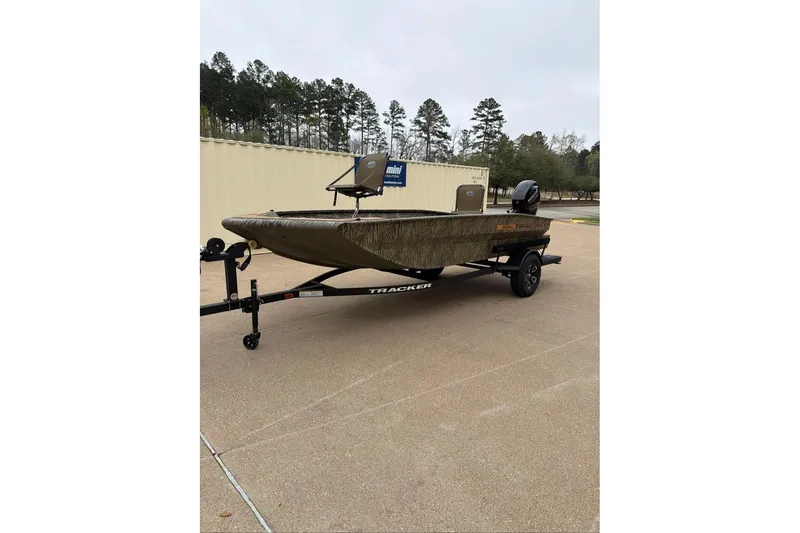 The Image of 2026 Tracker Grizzly 1756 T Marsh boat on trailer, outdoors with trees in background. - 0
