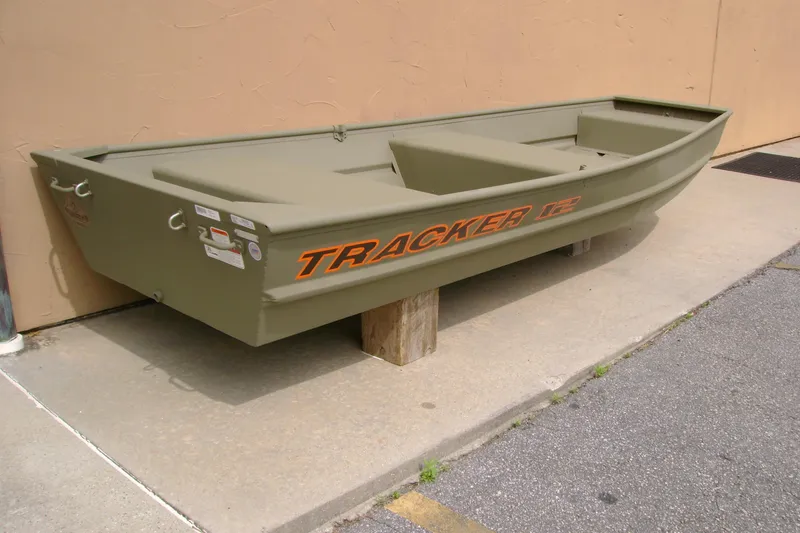 Slide: The Image of 2026 Tracker Grizzly 12 Jon boat in olive green, displayed outdoors on concrete. - 2