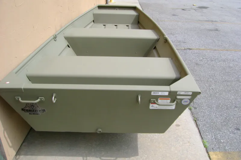 Slide: The Image of 2026 Tracker Grizzly 12 Jon boat, olive green, parked on concrete surface. - 4