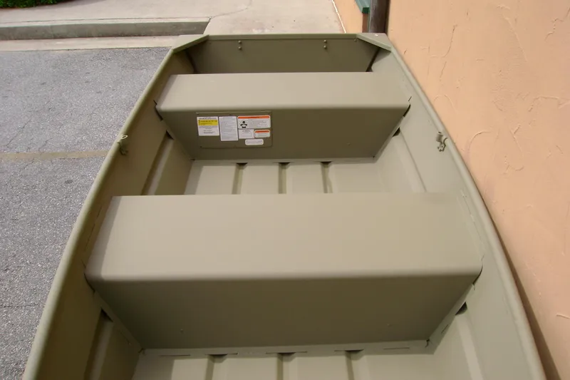 Slide: The Image of 2026 Tracker Grizzly 12 Jon boat interior with bench seats and safety labels. - 5