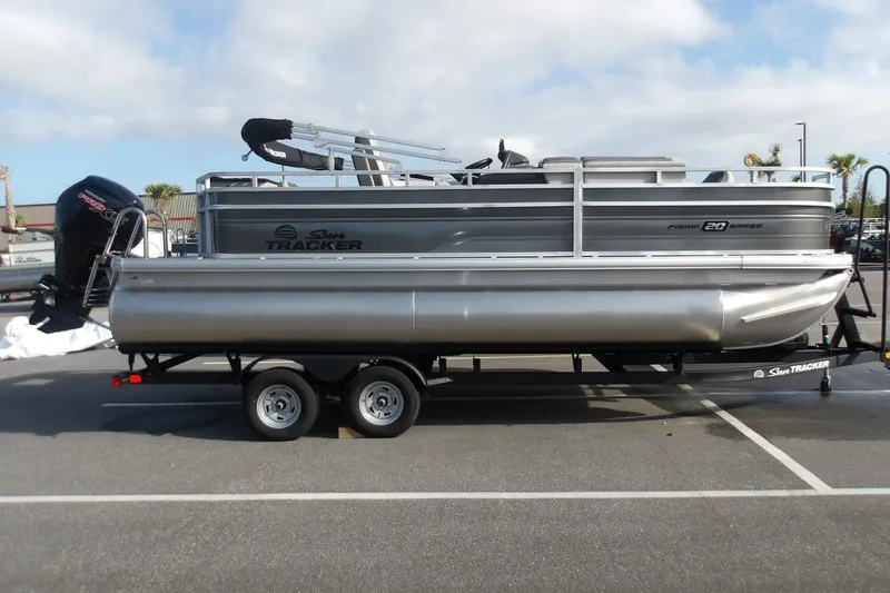 The Image of 2026 Sun Tracker Fishin' Barge 20 DLX pontoon boat on trailer in parking lot. - 0