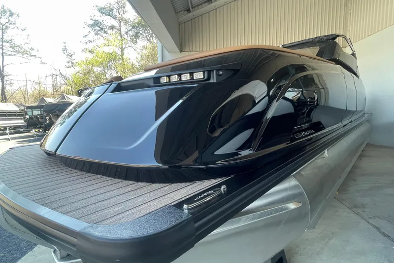 Slide: The Image of 2026 Harris Crowne SL 250 pontoon boat with sleek black design in a showroom. - 25