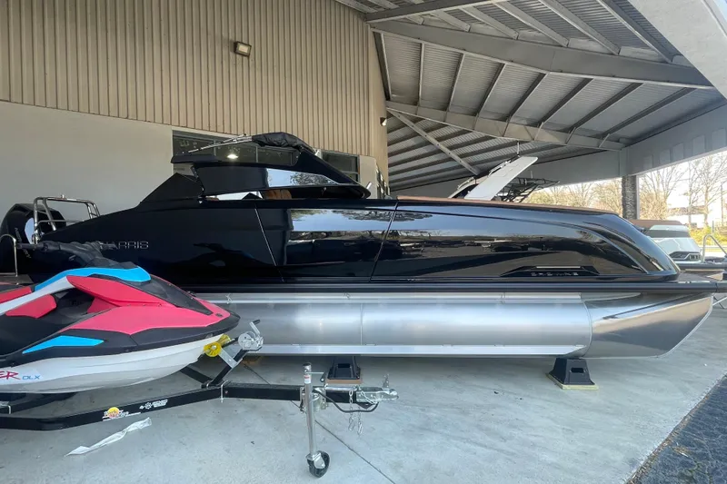 Slide: The Image of 2026 Harris Crowne SL 250 pontoon boat displayed in a showroom with a jet ski. - 26