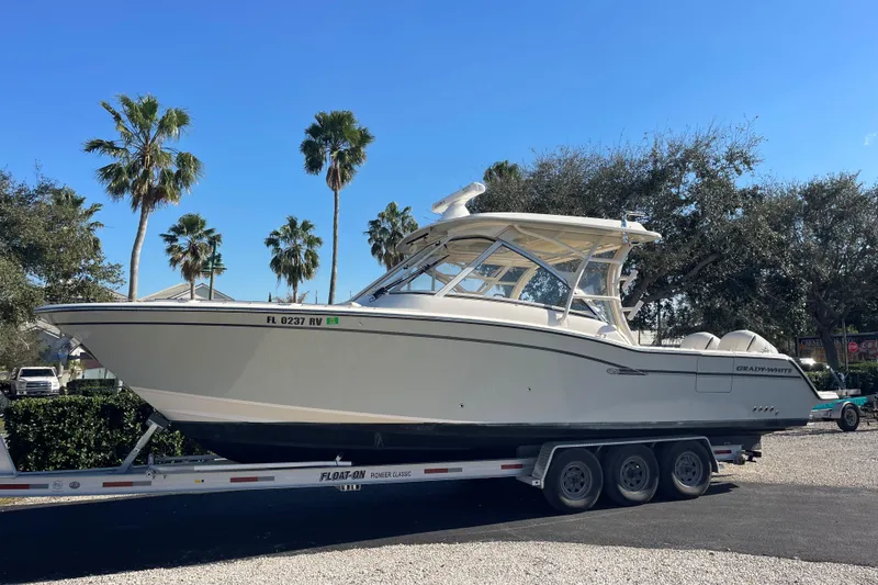 The Image of 2019 Grady-White Freedom 325 boat on trailer, surrounded by palm trees under clear blue sky. - 0