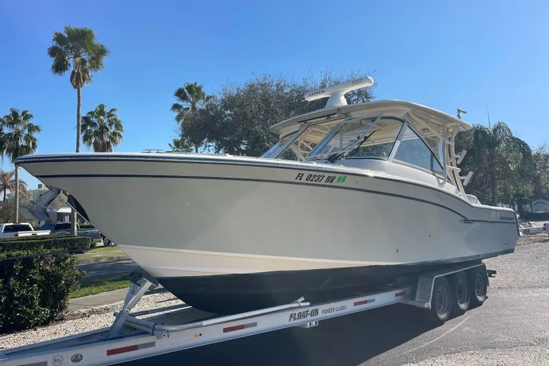 Slide: The Image of 2019 Grady-White Freedom 325 boat on trailer, sunny day, palm trees in background. - 2