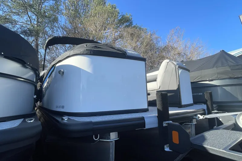 Slide: The Image of 2026 Harris Sunliner 230 pontoon boat, white exterior, parked outdoors under clear blue sky. - 12