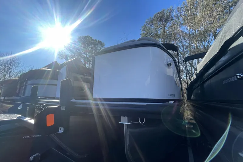 Slide: The Image of 2026 Harris Sunliner 230 pontoon boat under bright sun, surrounded by trees. - 13