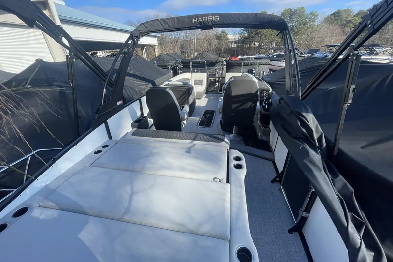 Slide: The Image of 2026 Harris Sunliner 230 boat interior with seating and helm, docked outdoors. - 17