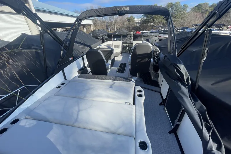 Slide: The Image of 2026 Harris Sunliner 230 boat interior with seating and helm, under a sunny sky. - 19