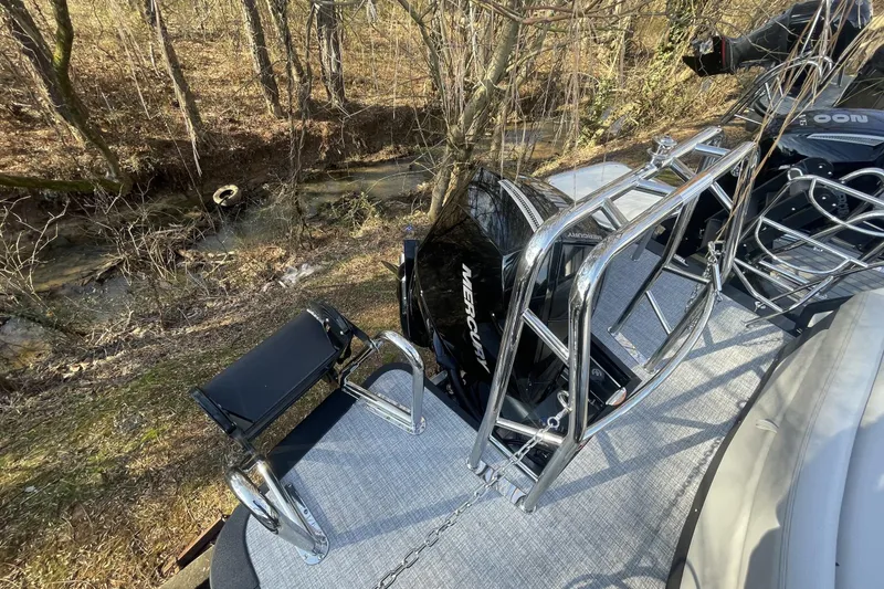 Slide: The Image of 2026 Harris Sunliner 230 boat with chrome ladder and Mercury engine near wooded stream. - 21