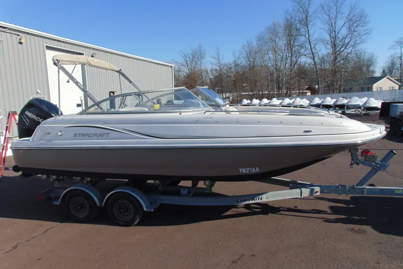 The Image of 2008 Starcraft 2210 OB Limited boat on trailer, parked outdoors near a building. - 1