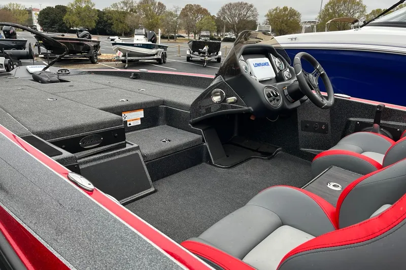 Slide: The Image of 2024 Triton 179 TrX boat interior with steering console and seating, parked outdoors. - 4