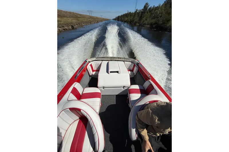 Slide: The Image of 1975 Sleekcraft Executive 23 boat cruising on a narrow waterway, featuring red and white interior. - 2