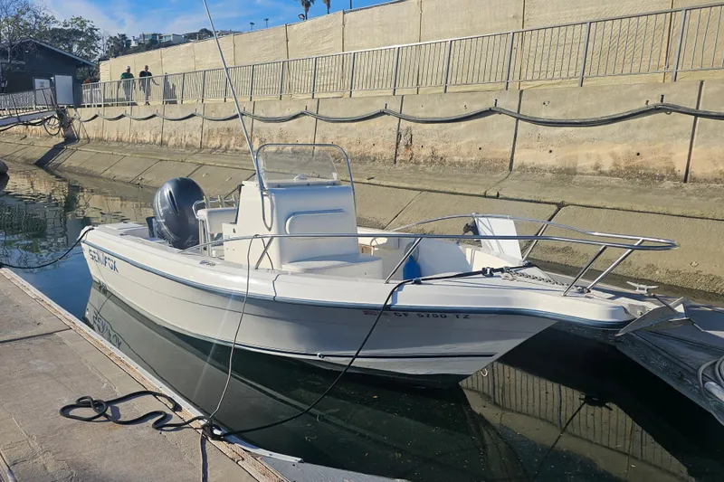 Slide: The Image of 2002 Sea Fox 210 Center Console boat docked in a canal on a sunny day. - 2