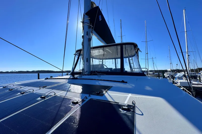 Slide: The Image of 2023 Lagoon 50 catamaran with solar panels docked under clear blue sky. - 10