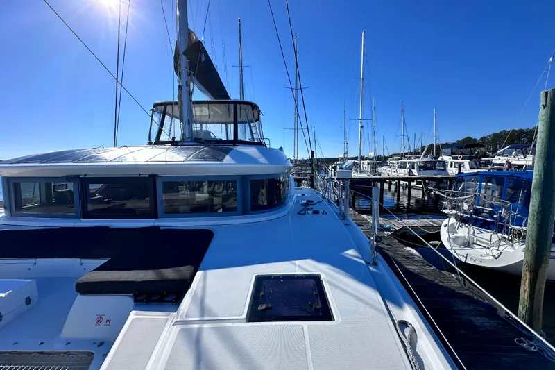 Slide: The Image of 2023 Lagoon 50 catamaran docked at marina under clear blue sky. - 11