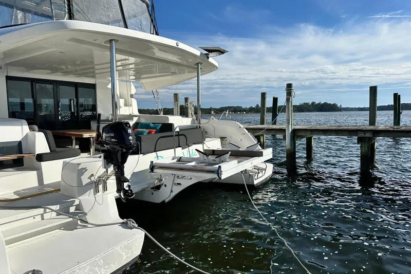 Slide: The Image of 2023 Lagoon 50 catamaran docked by a serene waterfront under a clear blue sky. - 16