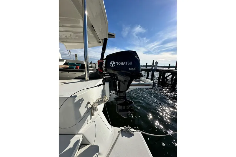 Slide: The Image of 2023 Lagoon 50 catamaran with Tohatsu outboard motor, docked by the water. - 17
