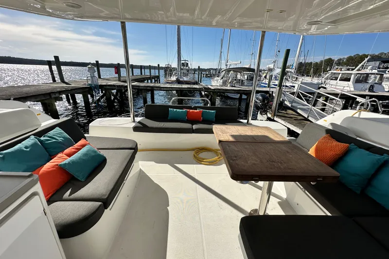 Slide: The Image of 2023 Lagoon 50 yacht interior with colorful cushions, docked at a marina. - 18