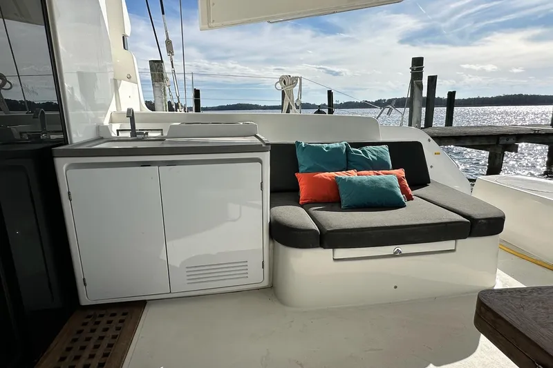 Slide: The Image of 2023 Lagoon 50 yacht deck with seating, cushions, and outdoor sink by the water. - 21