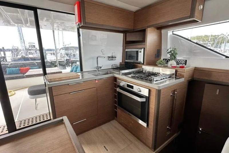 Slide: The Image of Modern kitchen interior of 2023 Lagoon 50 yacht with wood finish and stainless steel appliances. - 22