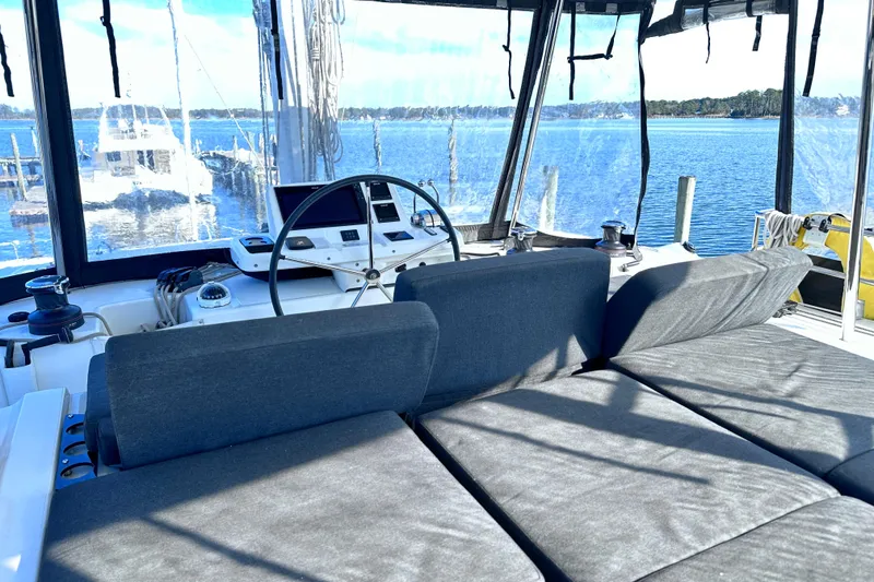 Slide: The Image of 2023 Lagoon 50 yacht cockpit with steering wheel and seating, overlooking serene waters. - 7
