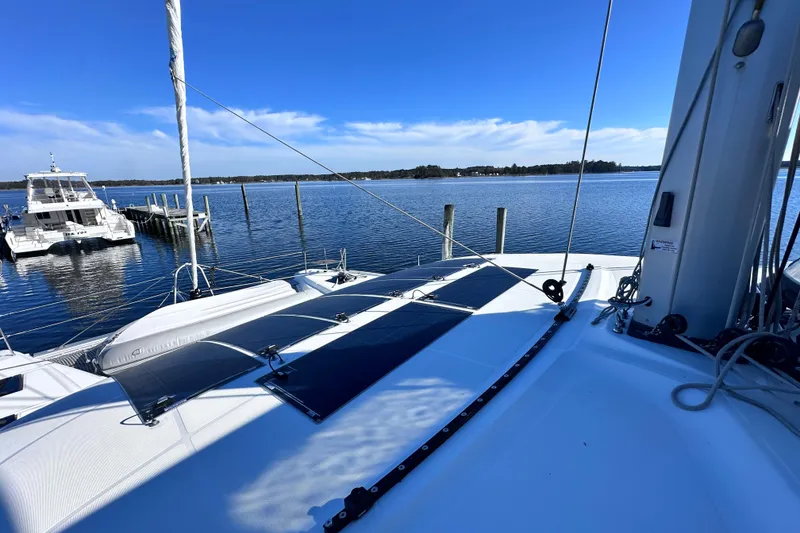 Slide: The Image of 2023 Lagoon 50 catamaran docked on serene water under clear blue sky. - 9