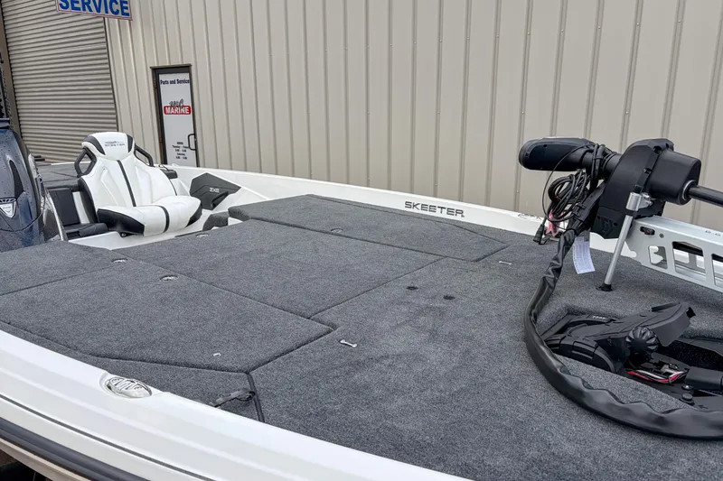 Slide: The Image of 2026 Skeeter ZXE21 boat with spacious deck and modern seating at a service center. - 4