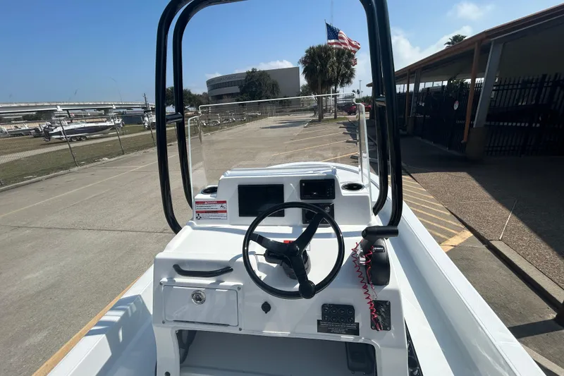 Slide: The Image of 2026 Shallow Sport 18 Sport boat dashboard with steering wheel and controls, outdoor setting. - 10